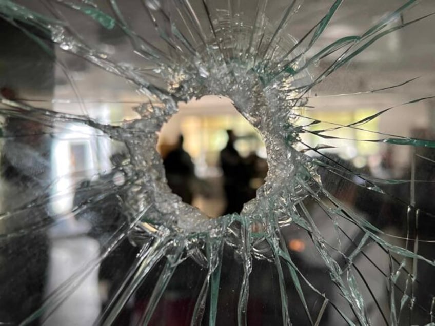 A large bullet hole frames journalists in the communal dining hall of Kibbutz Nir Oz, Isra