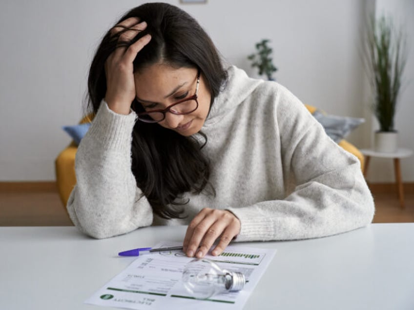 Woman looks worried while checking electricity bill at home.