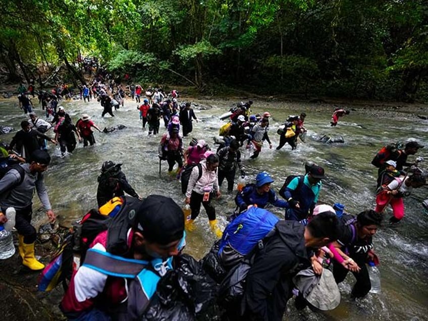 Migrants, mostly Venezuelans, cross a river during their journey through the Darien Gap fr