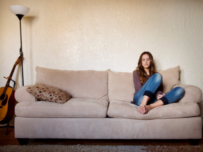 Upset woman sitting on sofa at home - stock photo USA, New York State