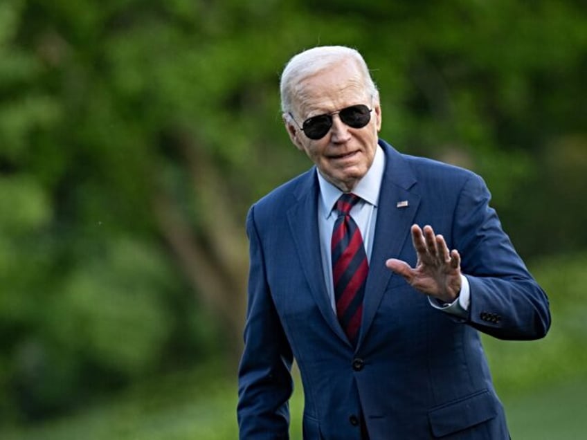 US President Joe Biden waves as he walks to the White House residence after exiting Marine