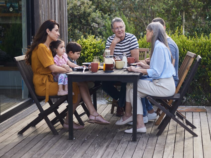 Smiling multi-generation family talking together over lunch while sitting around a dining