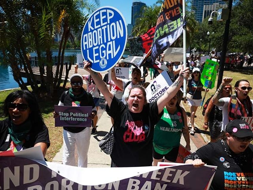 Emmie Reed (C) joins with other people as they walk together during a “Rally to Stop the