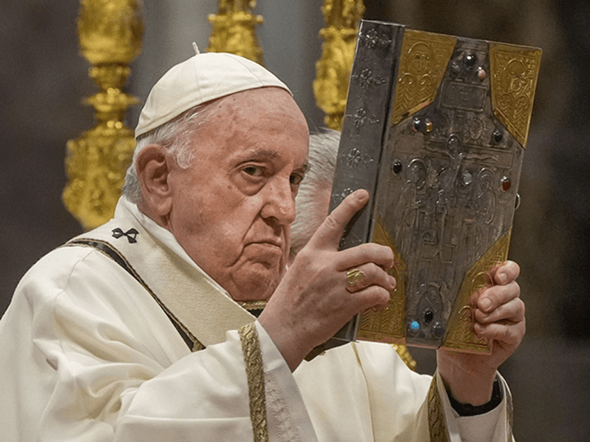 Pope Francis hoists the Gospel book during a Chrism Mass inside St. Peter's Basilica, at t