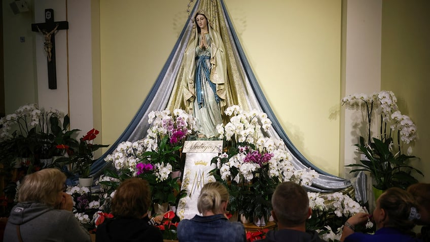 A statue of the Virgin Mary surrounded by flowers. 