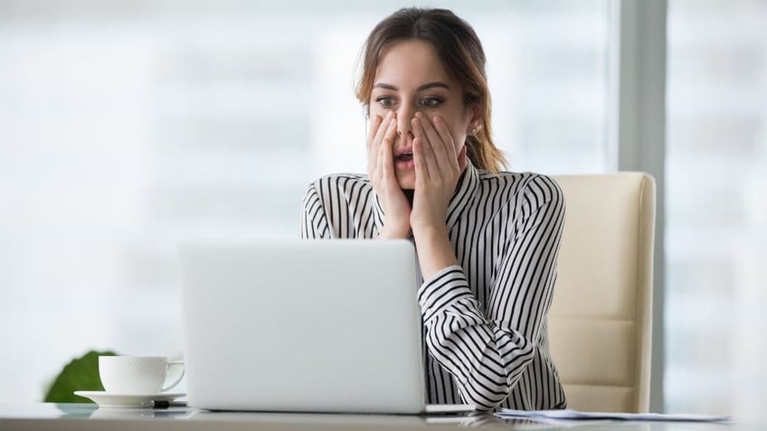 Woman staring at her laptop with a surprised face.