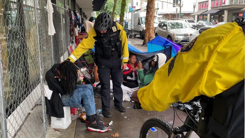 Officer David Baer asks a man on the sidewalk if he's okay