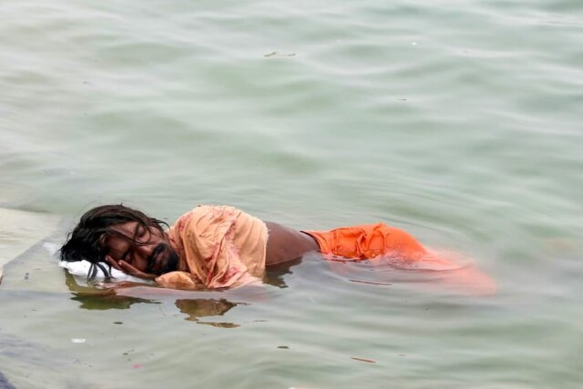 A man in India sleeps in the River Ganges in Varanasi on June 18: much of northern India h