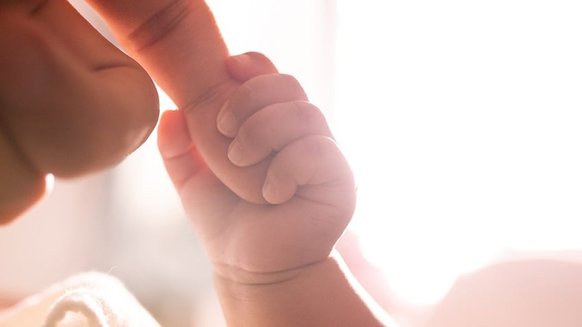 Baby holding mother's finger