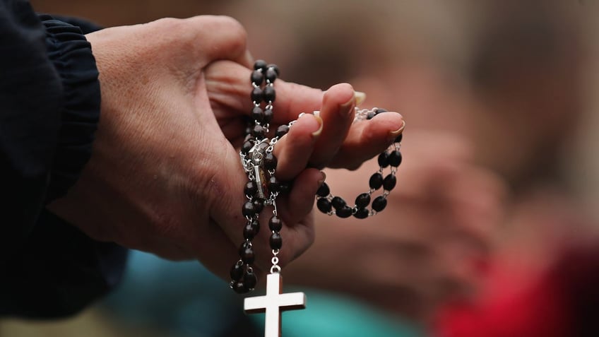 VATICAN CITY, VATICAN - MARCH 13: A woman holds rosary beads while she prays and waits for smoke to emanate from the chimney on the roof of the Sistine Chapel which will indicate whether or not the College of Cardinals have elected a new Pope on March 13, 2013 in Vatican City, Vatican. Pope Benedict XVI's successor is being chosen by the College of Cardinals in Conclave in the Sistine Chapel. The 115 cardinal-electors, meeting in strict secrecy, will need to reach a two-thirds-plus-one vote majority to elect the 266th Pontiff. (Photo by Dan Kitwood/Getty Images)