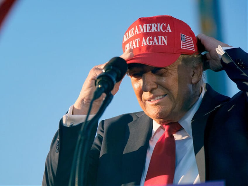 Republican presidential nominee former President Donald Trump puts on a campaign hat as he