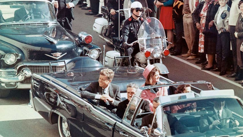 President and Mrs. John F. Kennedy smile at the crowds lining their motorcade route in Dallas, Texas, on Nov. 22, 1963. Minutes later, the president was assassinated as his car passed through Dealey Plaza.