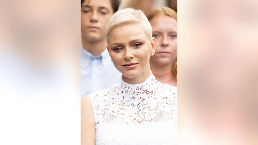 Princess Charlene wearing a lace white dress with no sleeves.