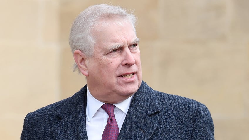 Prince Andrew looking away in a grey blazer, white shirt and a burgundy tie.