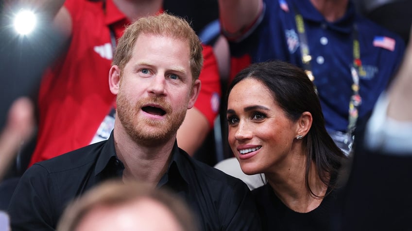 Prince Harry and Meghan Markle sitting together within an audience