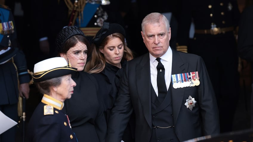 Prince Andrew wearing a black suit with medals standing with his two daughters and sister Princess Anne.