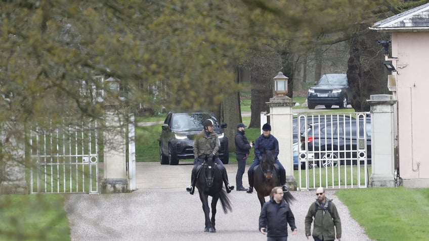 Prince Andrew on horseback exiting from open gates.