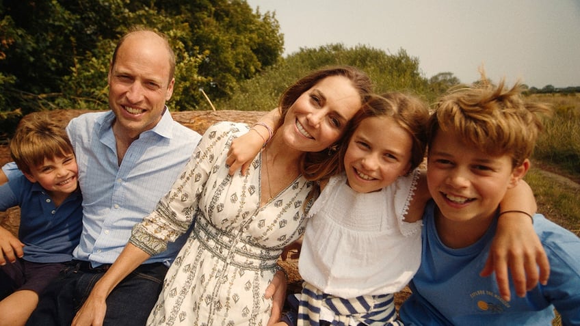 Prince Louis, Prince William, Princess Kate, Princess Charlotte, and Prince George all lean against each other for a family portrait