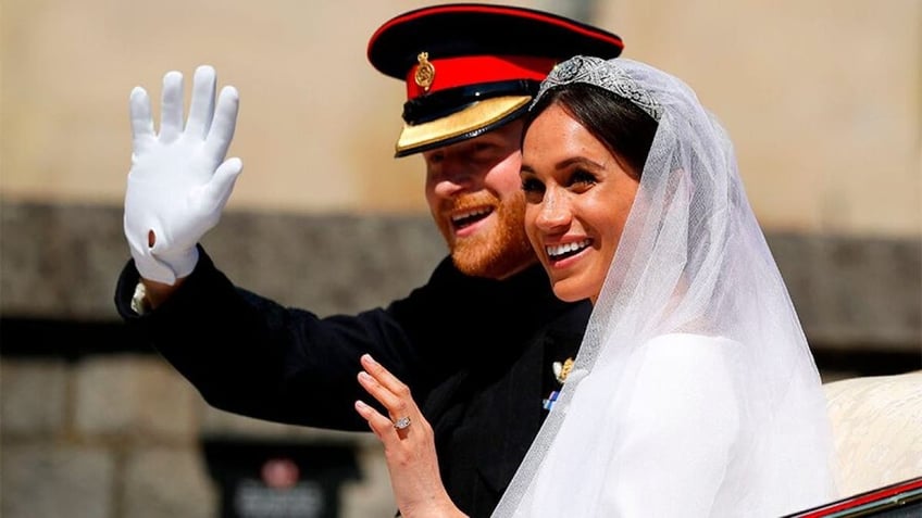 Meghan Markle in her bridal gown waving to a crowd next to her groom Prince Harry