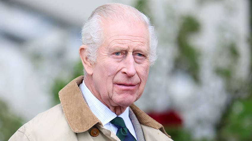 A close-up of King Charles in a trench coat.