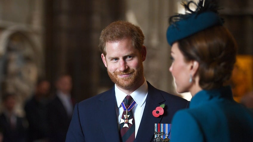 Prince Harry smiling at Kate Middleton as she speaks