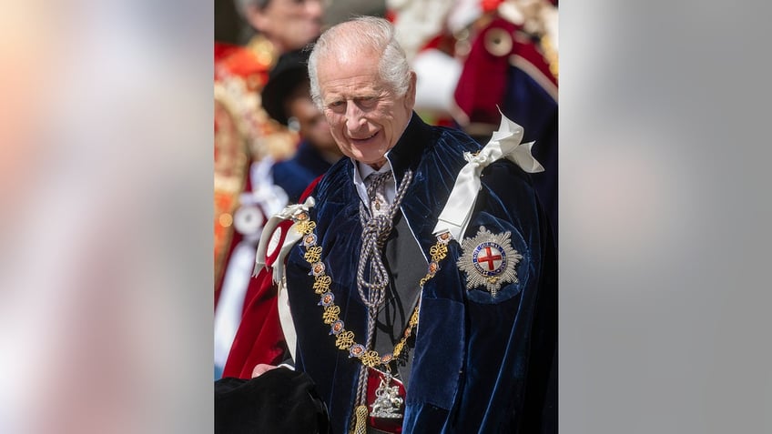 King Charles wearing royal robes and walking in public.