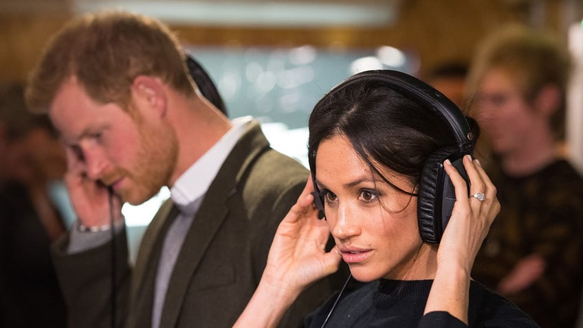 Prince Harry and Meghan Markle listening to headphones