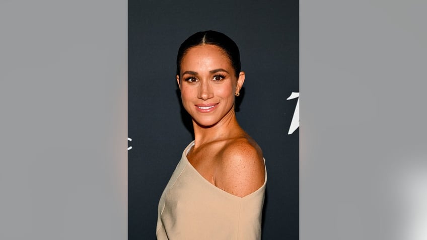 Meghan Markle wearing a beige off the shoulder dress on the red carpet