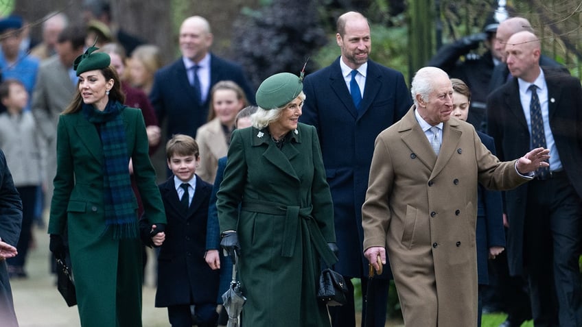 The royal family walking together outside the church wearing matching navy blue and green.