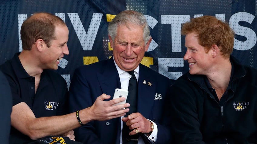 Prince William showing King Charles his iPhone as Prince Harry laughs