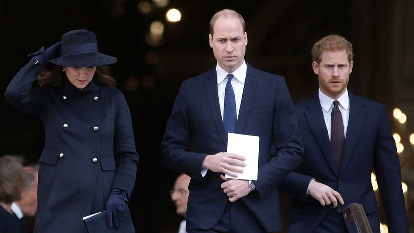 Kate Middleton, Prince William and Prince Harry walking in a row looking somber in dark clothing.