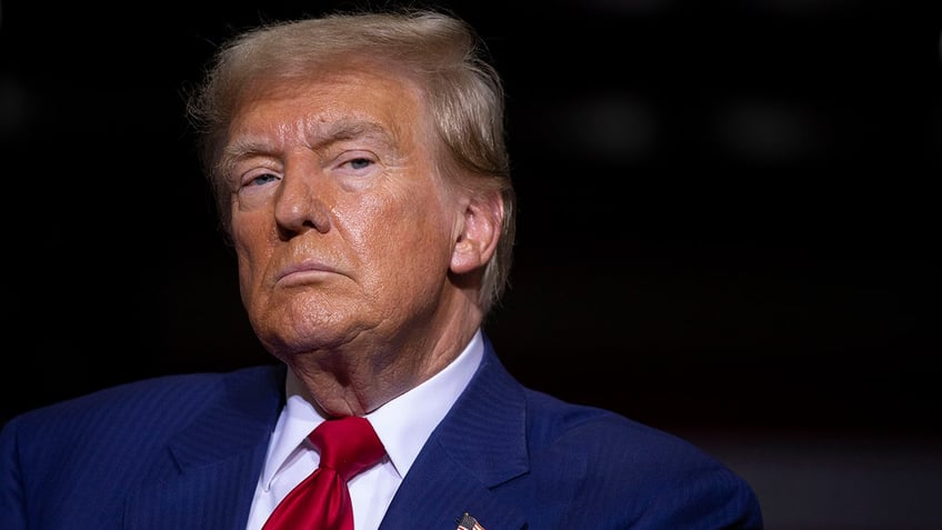 A close-up of Donald Trump wearing a navy blazer and a red tie.