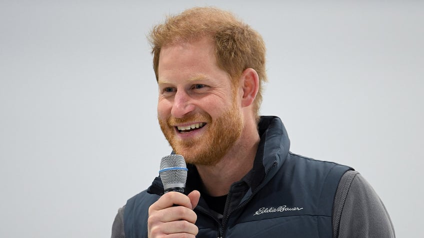 Prince Harry smiling and holding a microphone