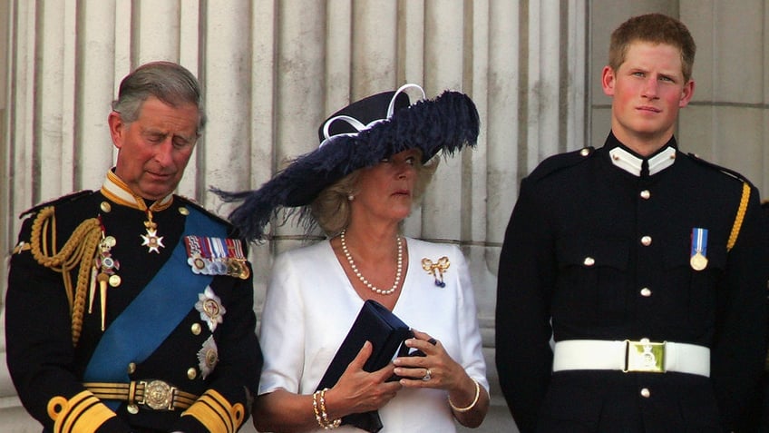 King Charles looking down as Queen Camilla looks up at a young Prince Harry in uniform.