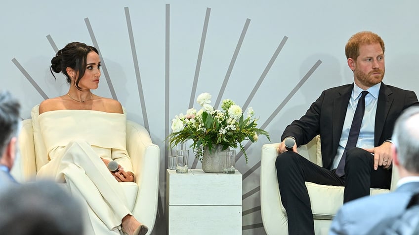 Meghan Markle and Prince Harry sitting next to each other looking serious at an event in New York City