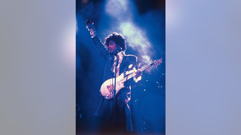 Prince on stage performing and holding a guitar