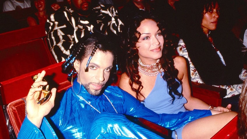 Prince in an electric blue suit sitting next to Mayte Garcia.