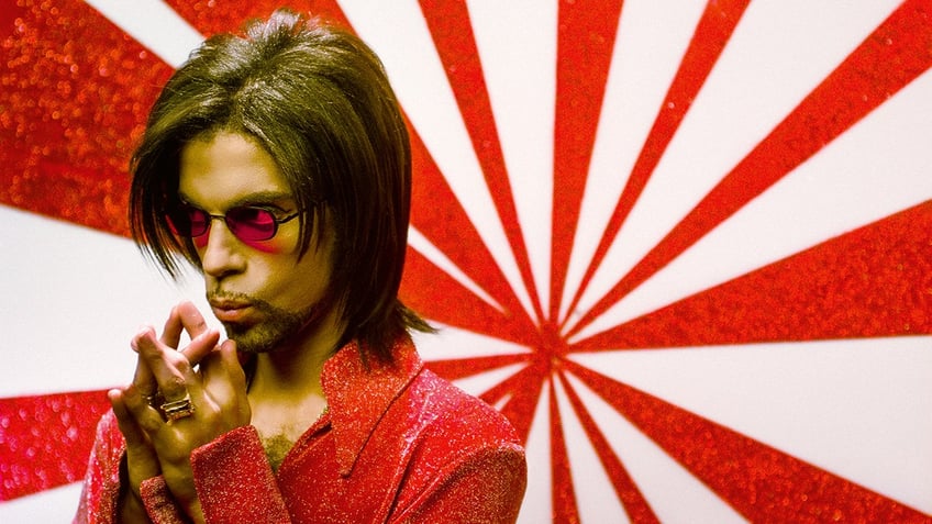 Prince wearing a red suit and matching glasses.