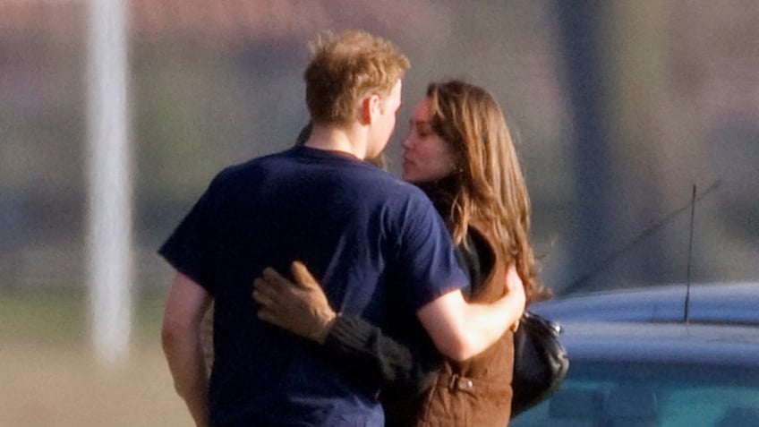 Prince William holding Kate Middleton as she leans in for a kiss.