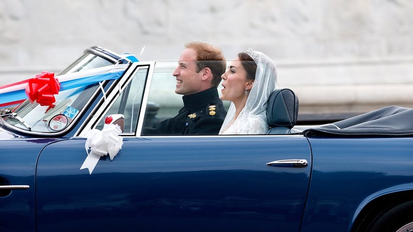 Prince William and Kate Middleton riding a blue car with the top down.