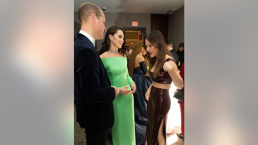 Prince William in a suit and Kate Middleton in a bright green dress talking to Ellie Goulding at a reception.