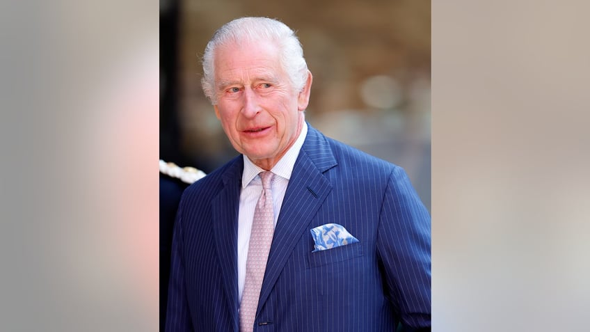 King Charles wearing a blue suit and a salmon pink tie