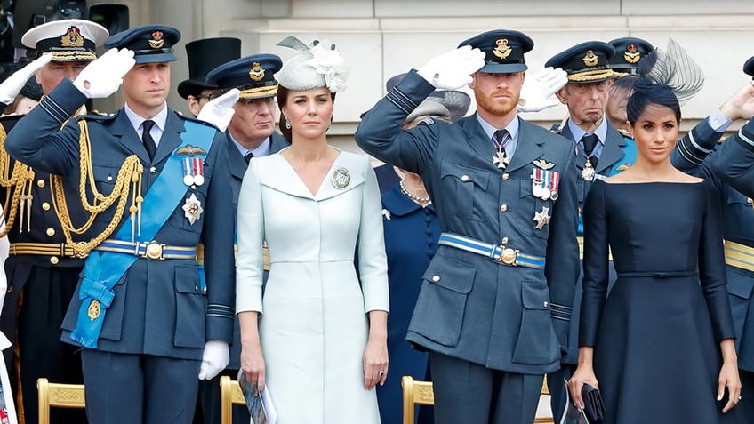 The royal family in formal attire standing in a line and looking serious.