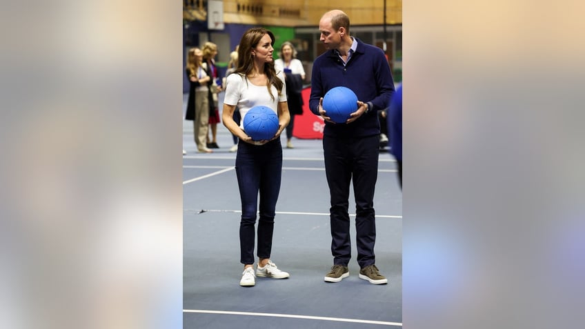 Kate Middleton and Prince William holding blue volleyballs