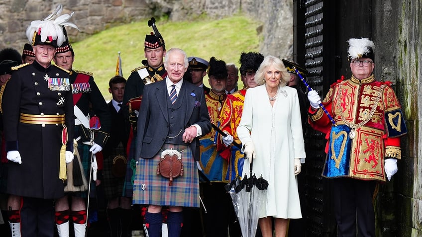 King Charles III and Queen Camilla posing with royal guards