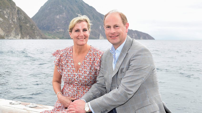 Sophia, Duchess of Edinburgh on a boat wearing a multiprinted dress sitting next to Prince Edward in a grey blazer and light blue shirt.