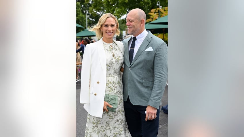 Zara Tindal in a floral dress with white jacket posing next to her husband Mike Tindall in a grey suit