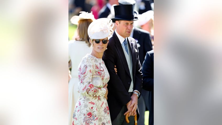 Zara Tindall in a floral dress and sunglasses with a fascinator standing next to Prince William in a suit and top hat.