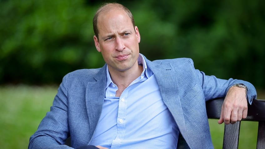 Prince William wearing a light blue blazer and a matching shirt looking serious