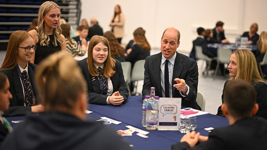 Prince William sitting with students at a high school